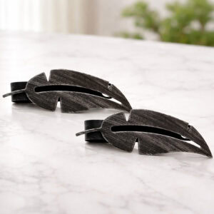 "Black brushed metal feather tiebacks on marble surface"