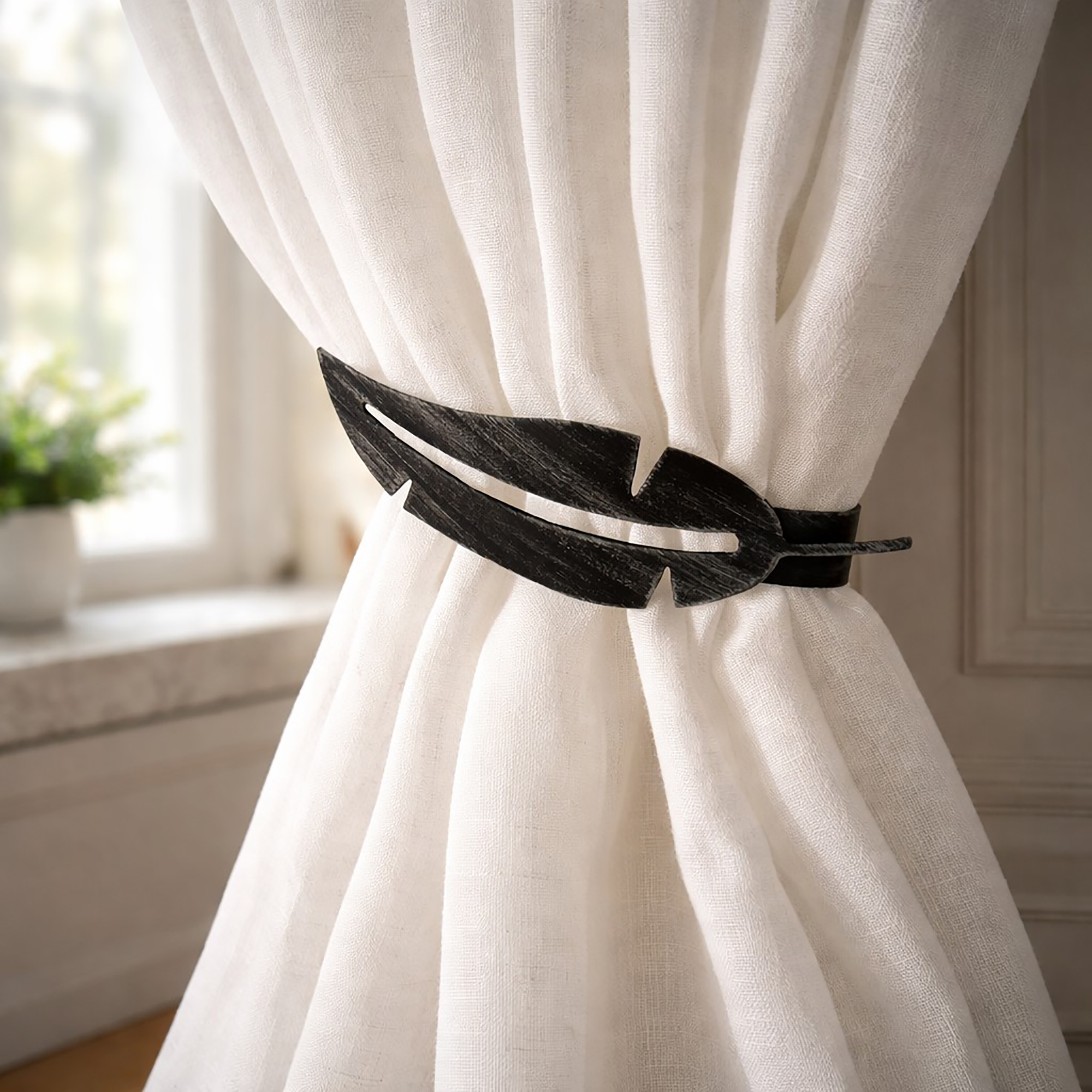 "Black feather metal tieback holding white curtain against wall"