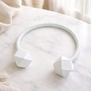 White braided curtain tieback with faceted wooden ends on marble surface