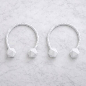 White braided curtain tiebacks with faceted wooden ends on marble surface