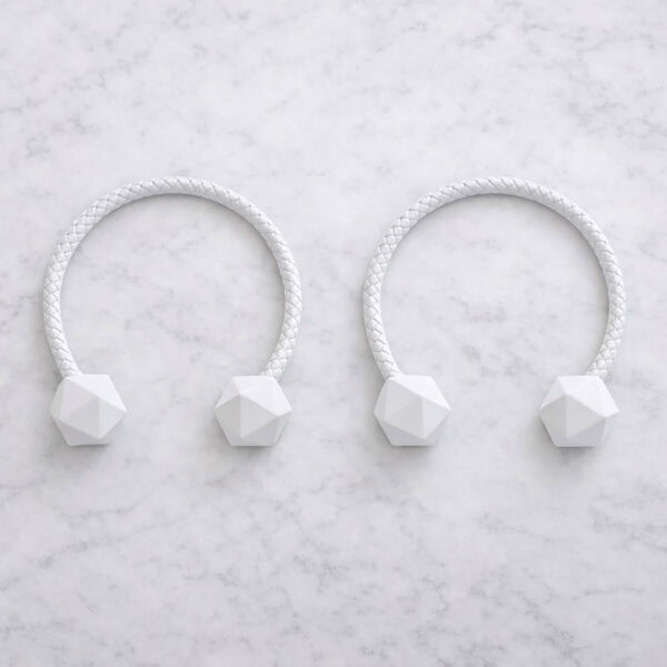 White braided curtain tiebacks with faceted wooden ends on marble surface