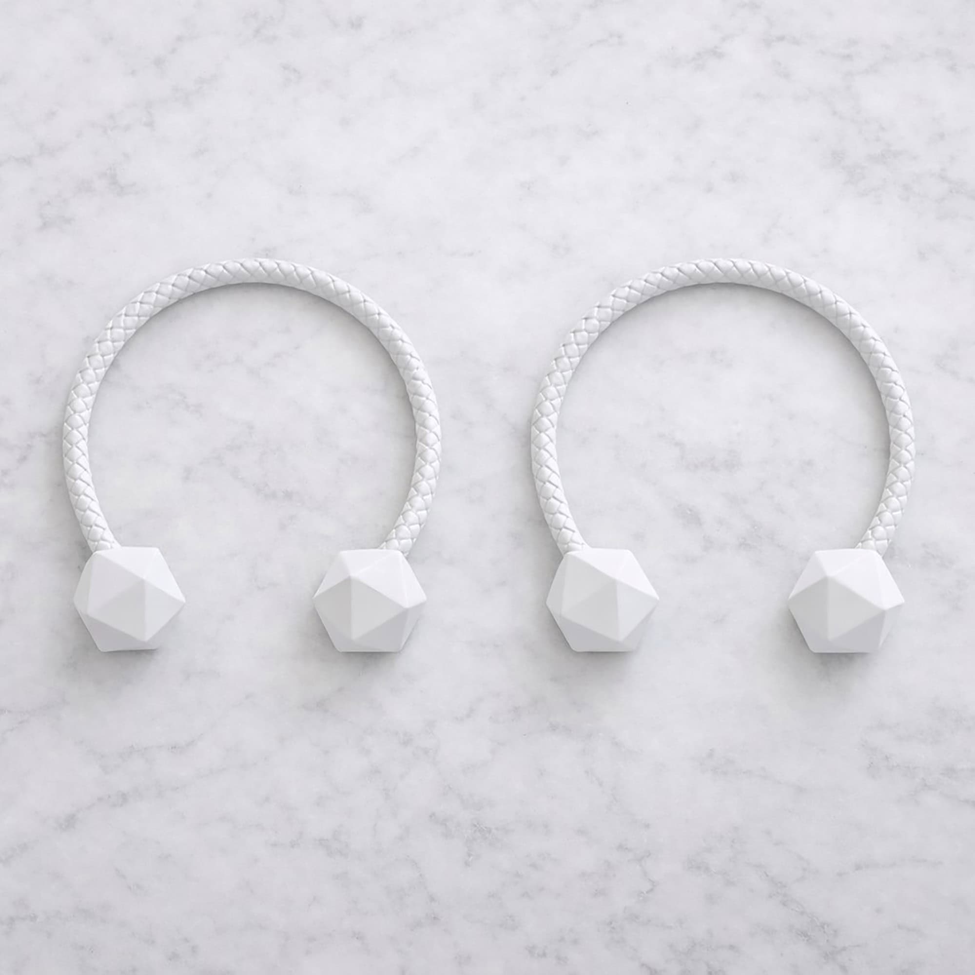 White braided curtain tiebacks with faceted wooden ends on marble surface