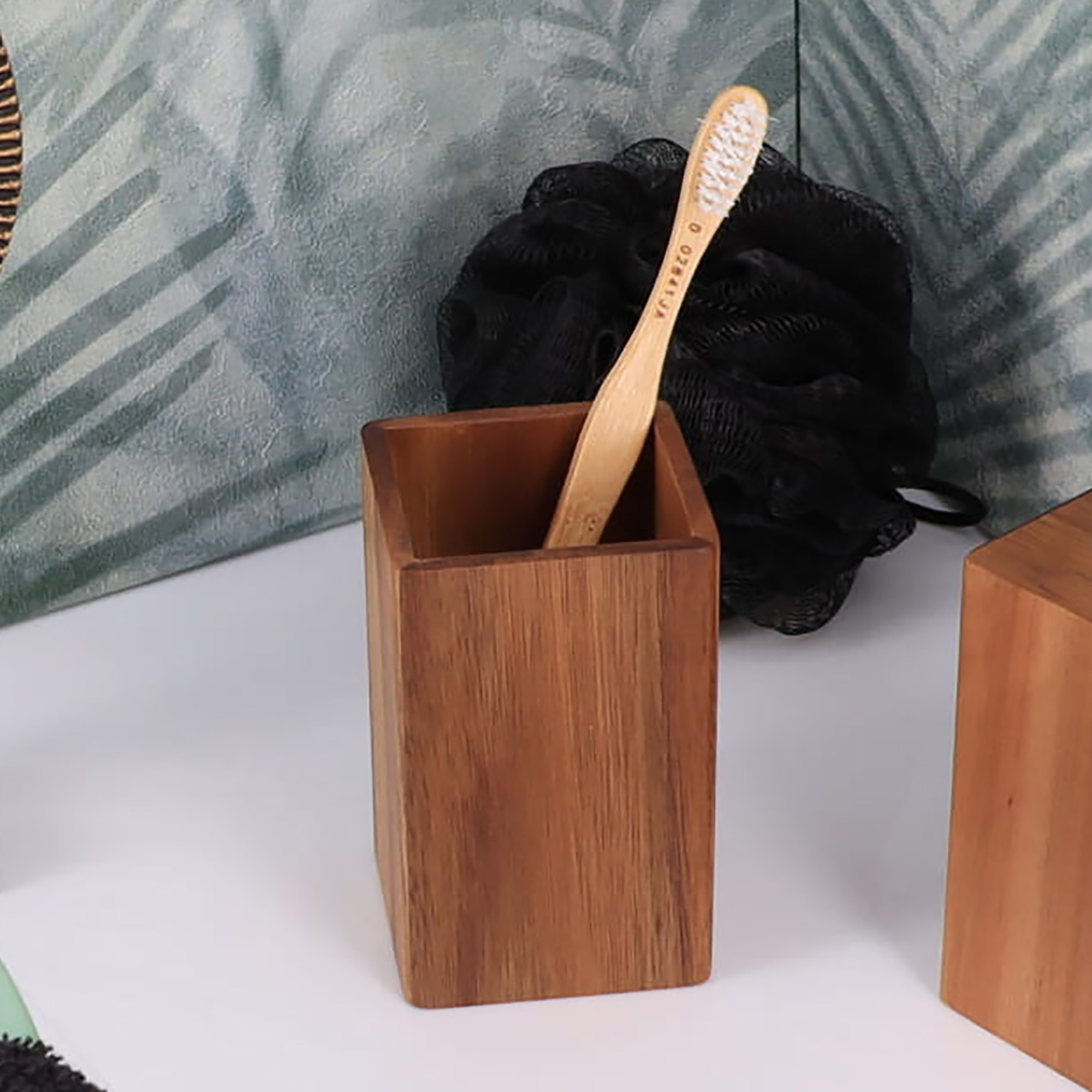 A wooden toothbrush holder placed on a bathroom counter with a bamboo toothbrush inside.