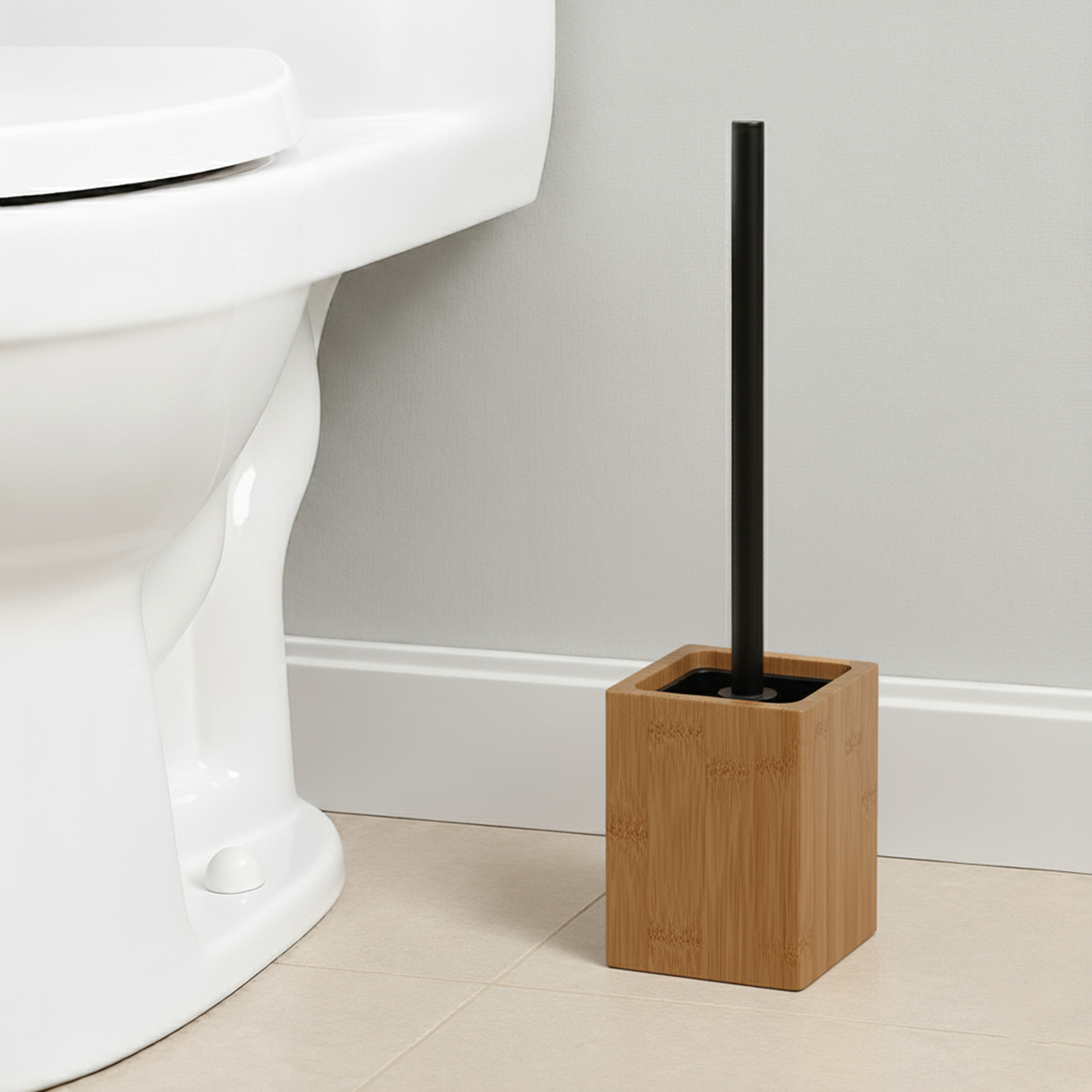 Wooden toilet brush with black handle in square acacia holder next to white toilet