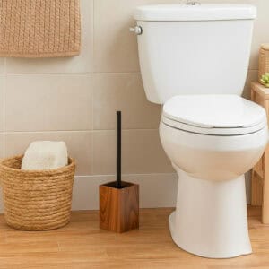 Wooden toilet brush holder in dark acacia wood beside white toilet and woven basket