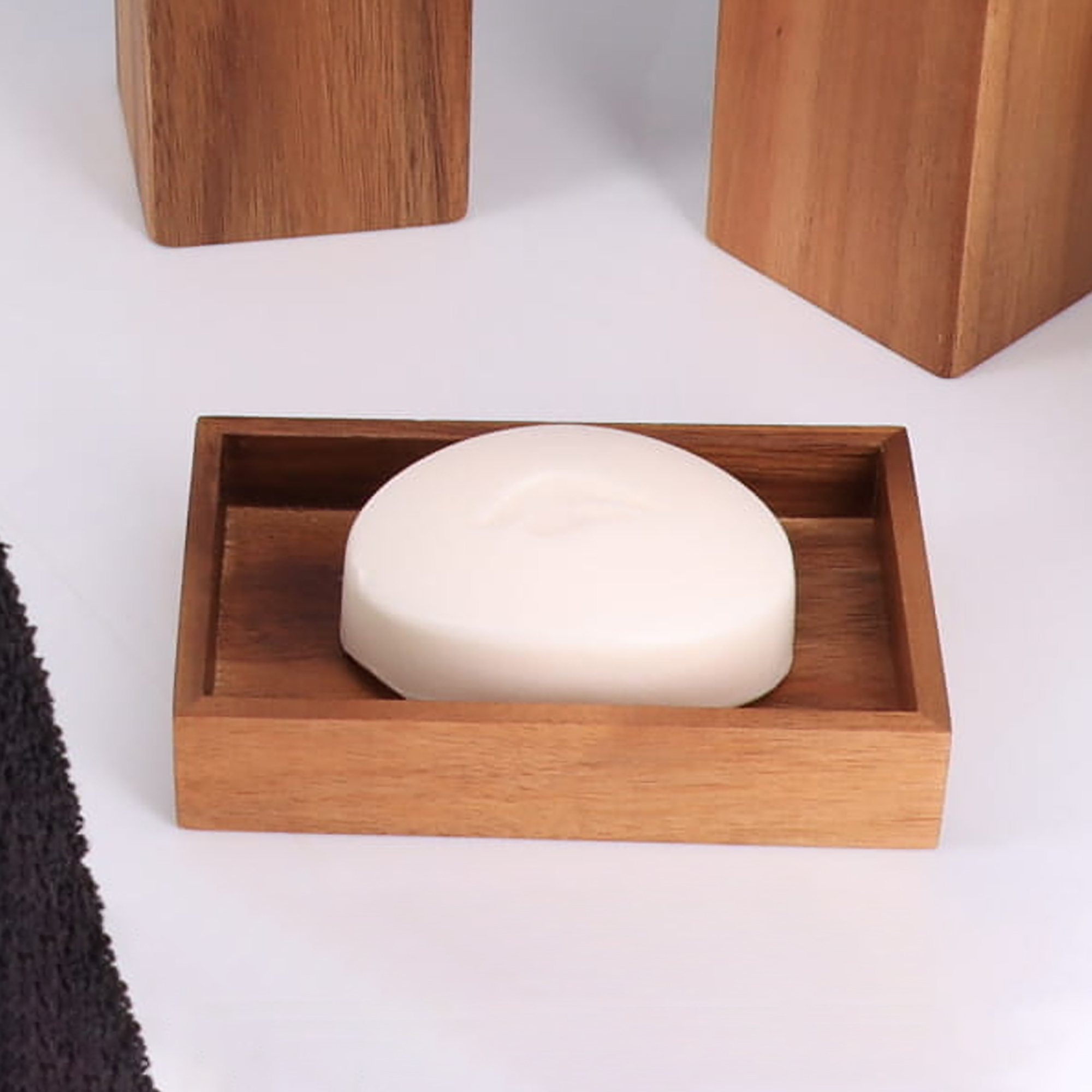 A wooden soap dish with a white soap bar, placed on a bathroom counter.