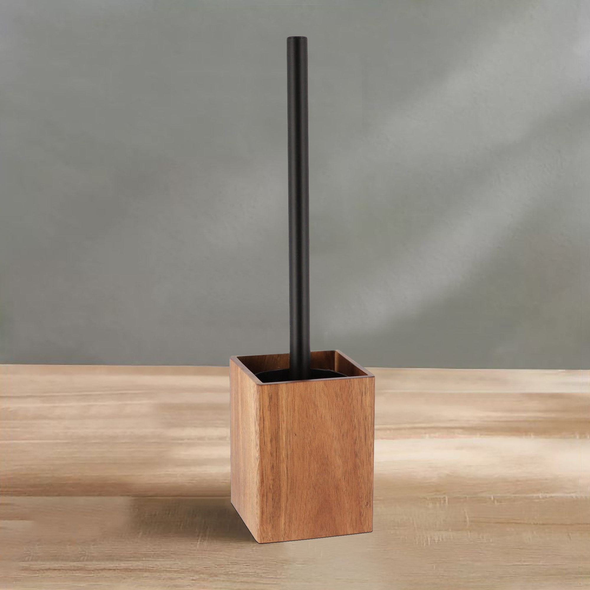 A wooden toilet brush holder with a black handle placed on a bathroom counter.