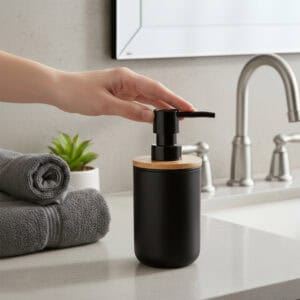 Hand pressing black soap dispenser pump on sink counter