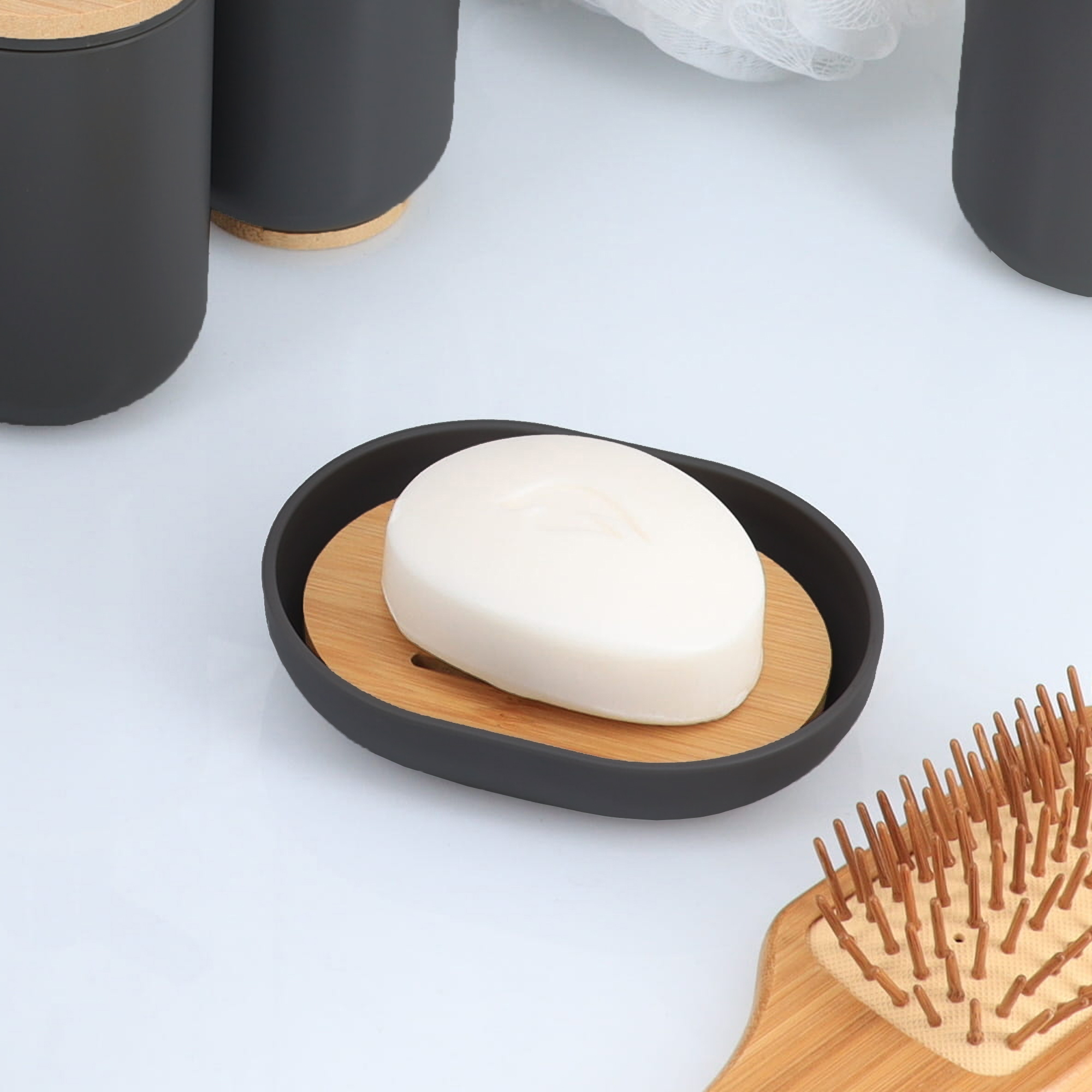 Black bamboo soap dish holding white soap bar among matching accessories