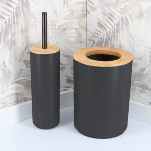 Matte black toilet brush and matching waste bin with bamboo lids against tropical leaf wallpaper