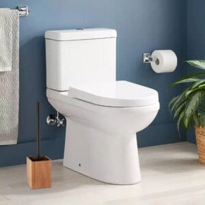 A wooden toilet brush holder placed next to a toilet in a modern bathroom.