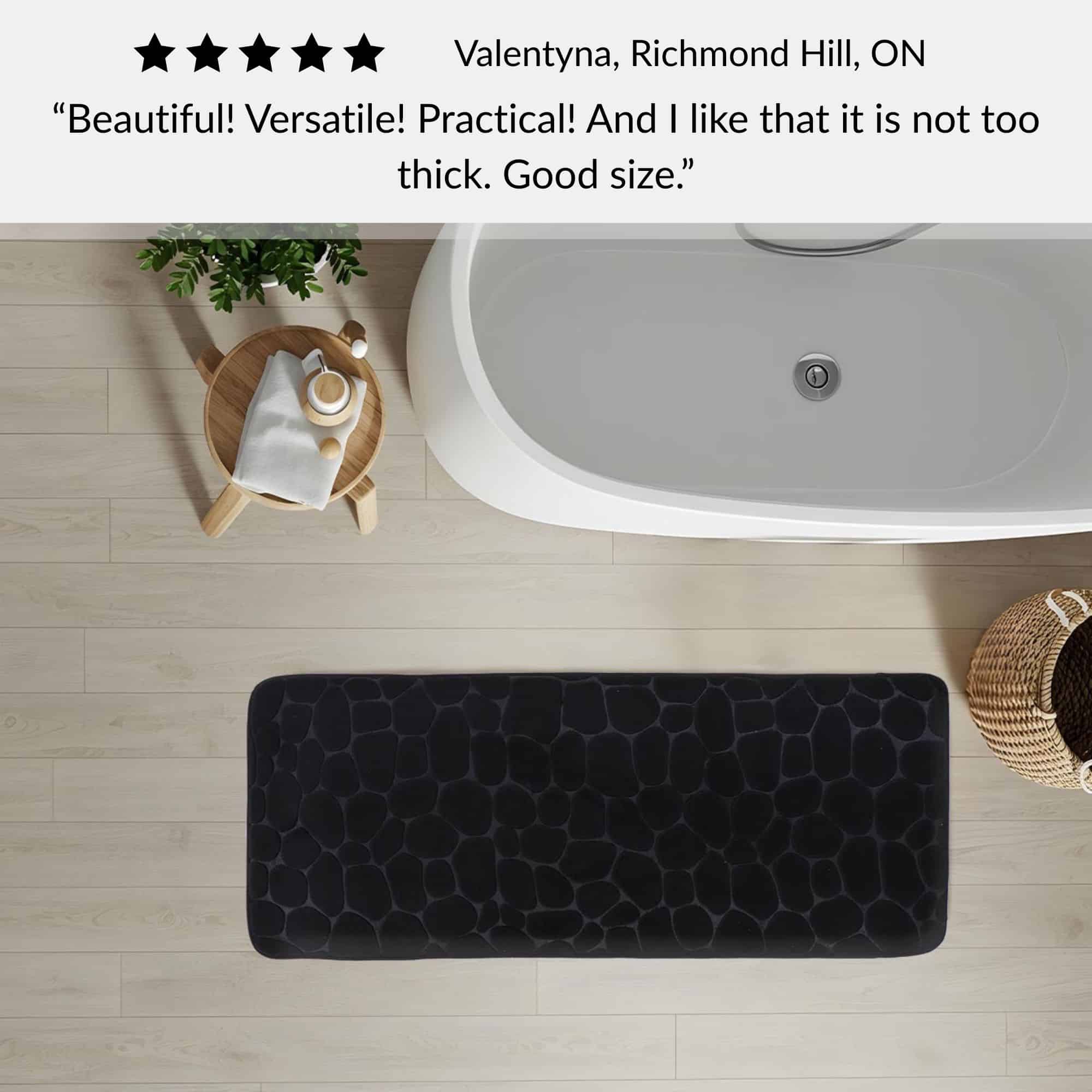 Black memory foam runner mat placed beside bathtub in spa-style bathroom with customer review highlighting versatility and size