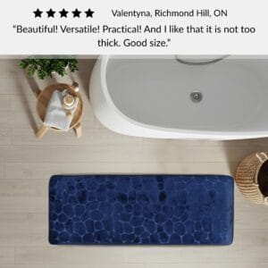 Navy blue memory foam runner mat placed beside bathtub in spa-style bathroom with customer review highlighting versatility and size