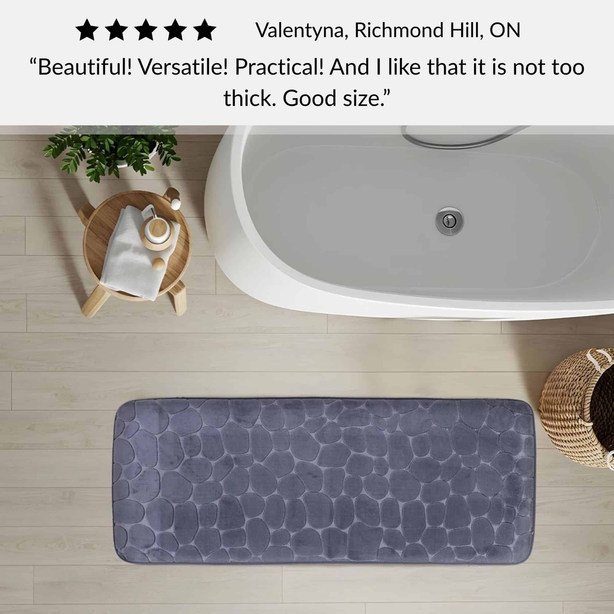 Dark gray memory foam runner mat placed beside bathtub in spa-style bathroom with customer review highlighting versatility and size