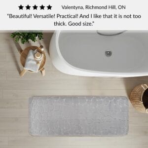 Light gray memory foam runner mat placed beside bathtub in spa-style bathroom with customer review highlighting versatility and size