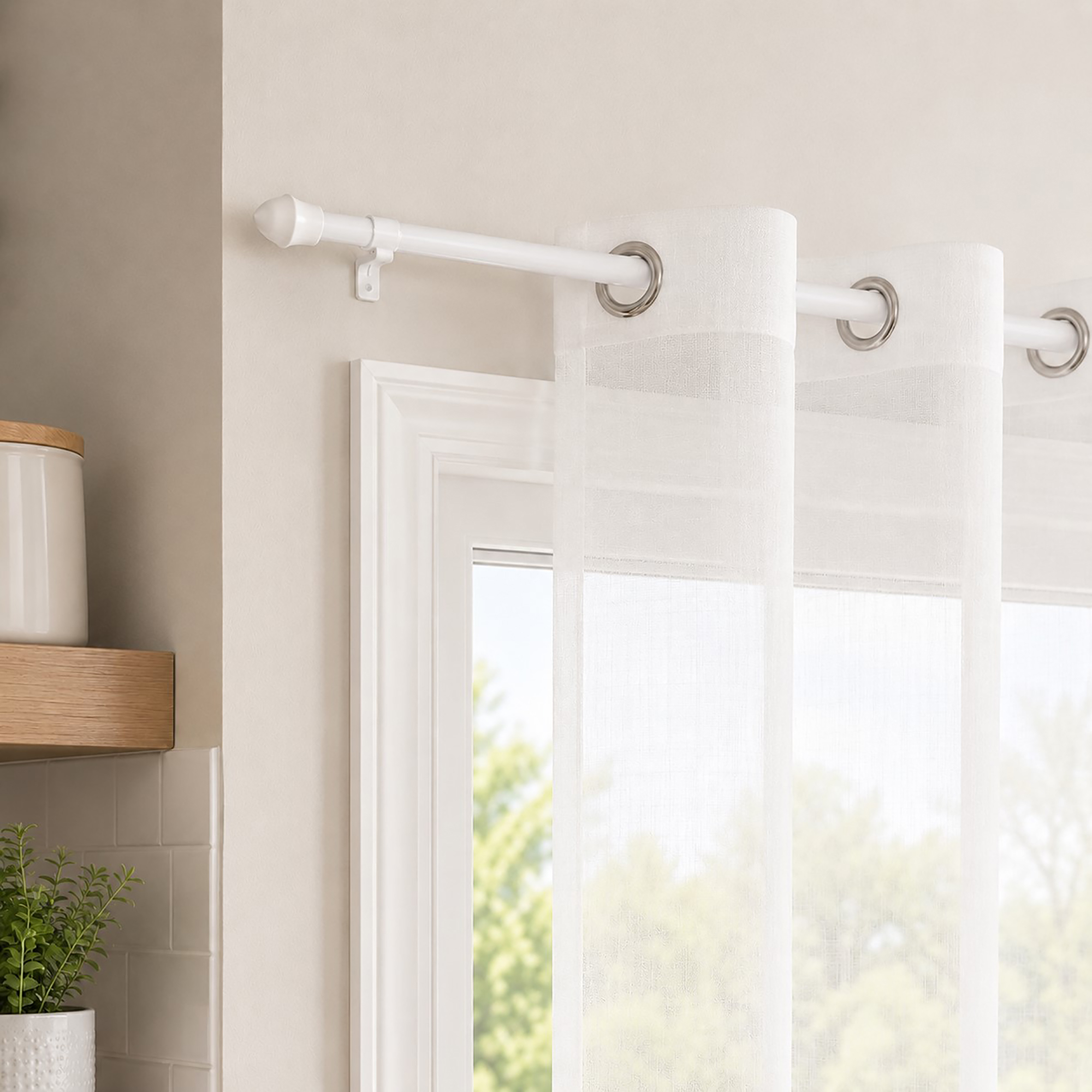 White cafe rod holding sheer white grommet curtains beside a trimmed kitchen window