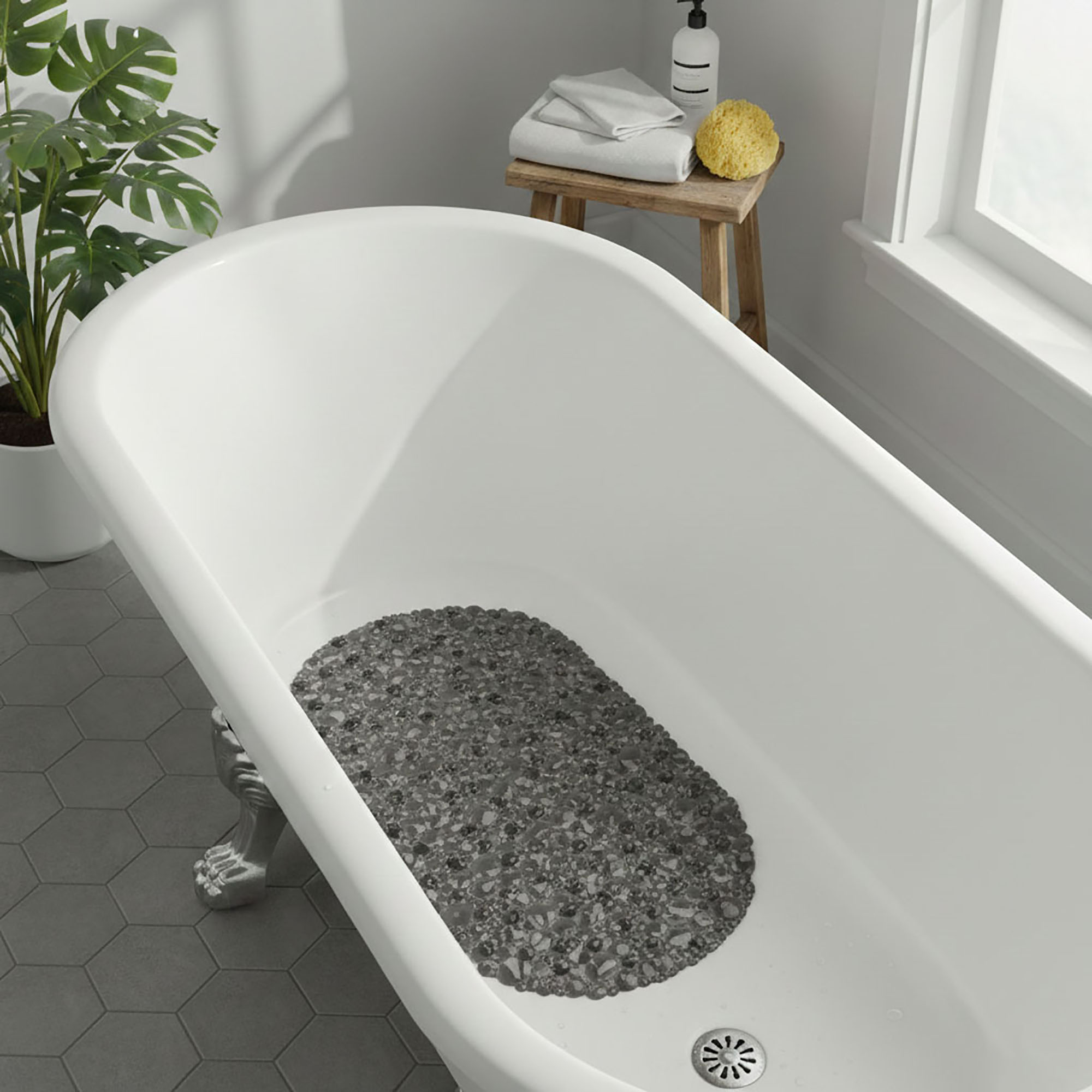 Gray pebble bath mat placed in white bathtub
