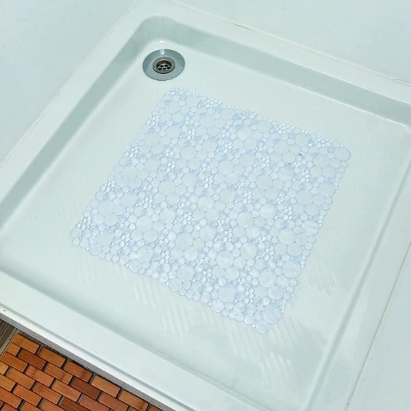 Clear bubble-pattern shower mat placed in white shower base with orange tile surround