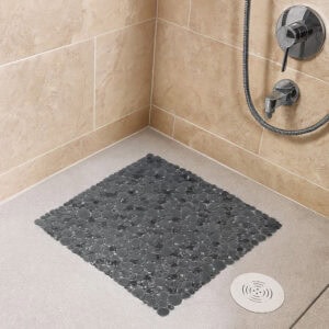 Gray bubble-pattern shower mat on beige tile shower floor with chrome fixtures
