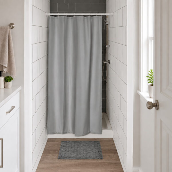 Gray half size shower curtain closing a narrow tiled shower stall in a small bright bathroom