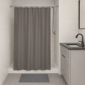 Grey stall-size shower curtain hanging in compact bathroom