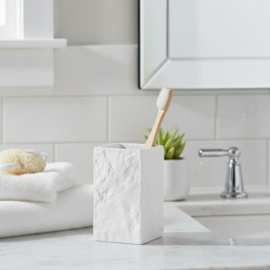 White stone effect bathroom tumbler with toothbrush on marble vanity