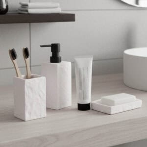 White stone effect bathroom accessories including soap dispenser tumbler soap dish and toothbrushes on vanity