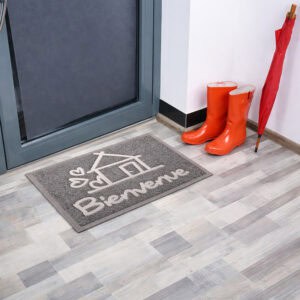 Angled indoor entryway view with gray Bienvenue doormat boots and umbrella