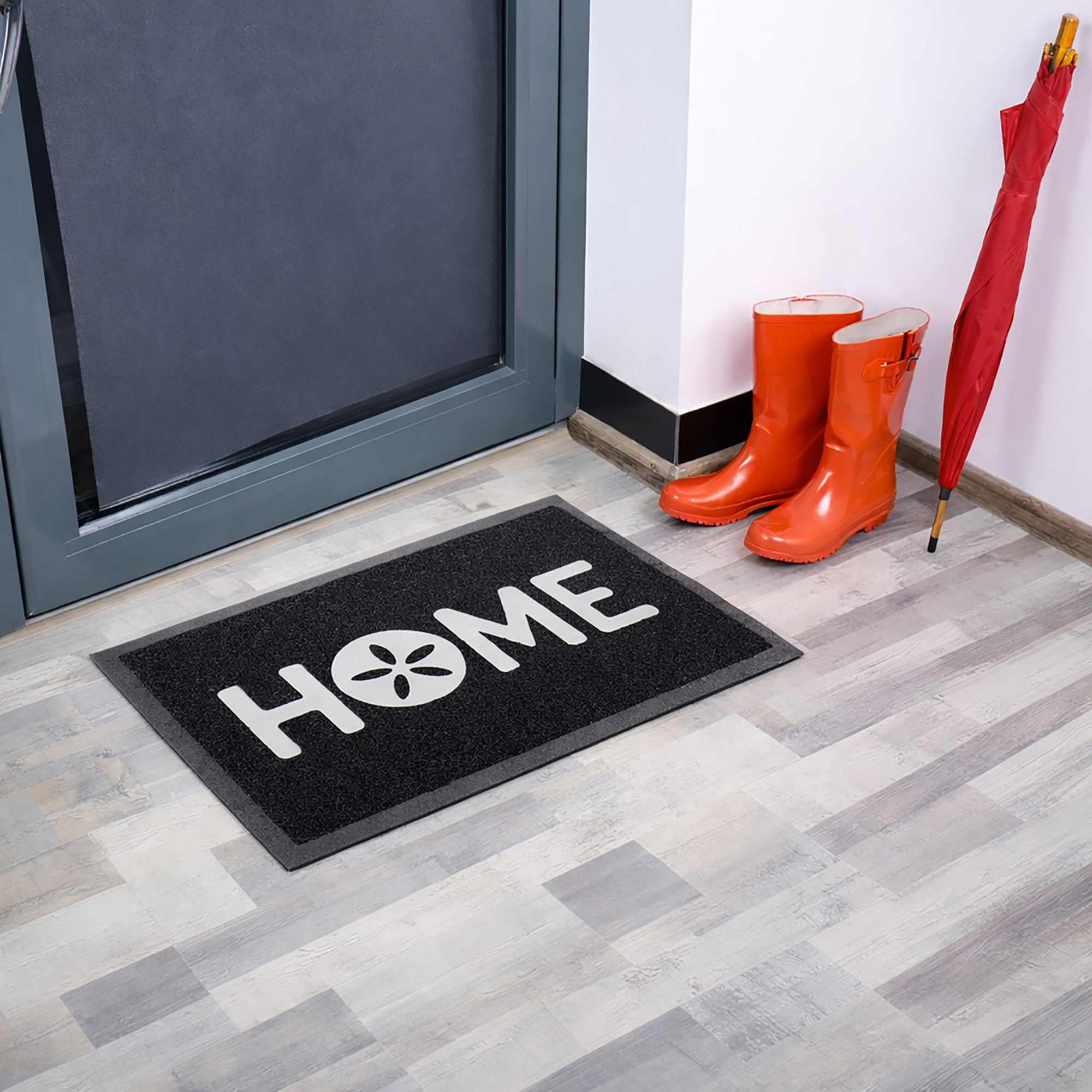 Angled indoor entryway view with black HOME doormat boots and umbrella