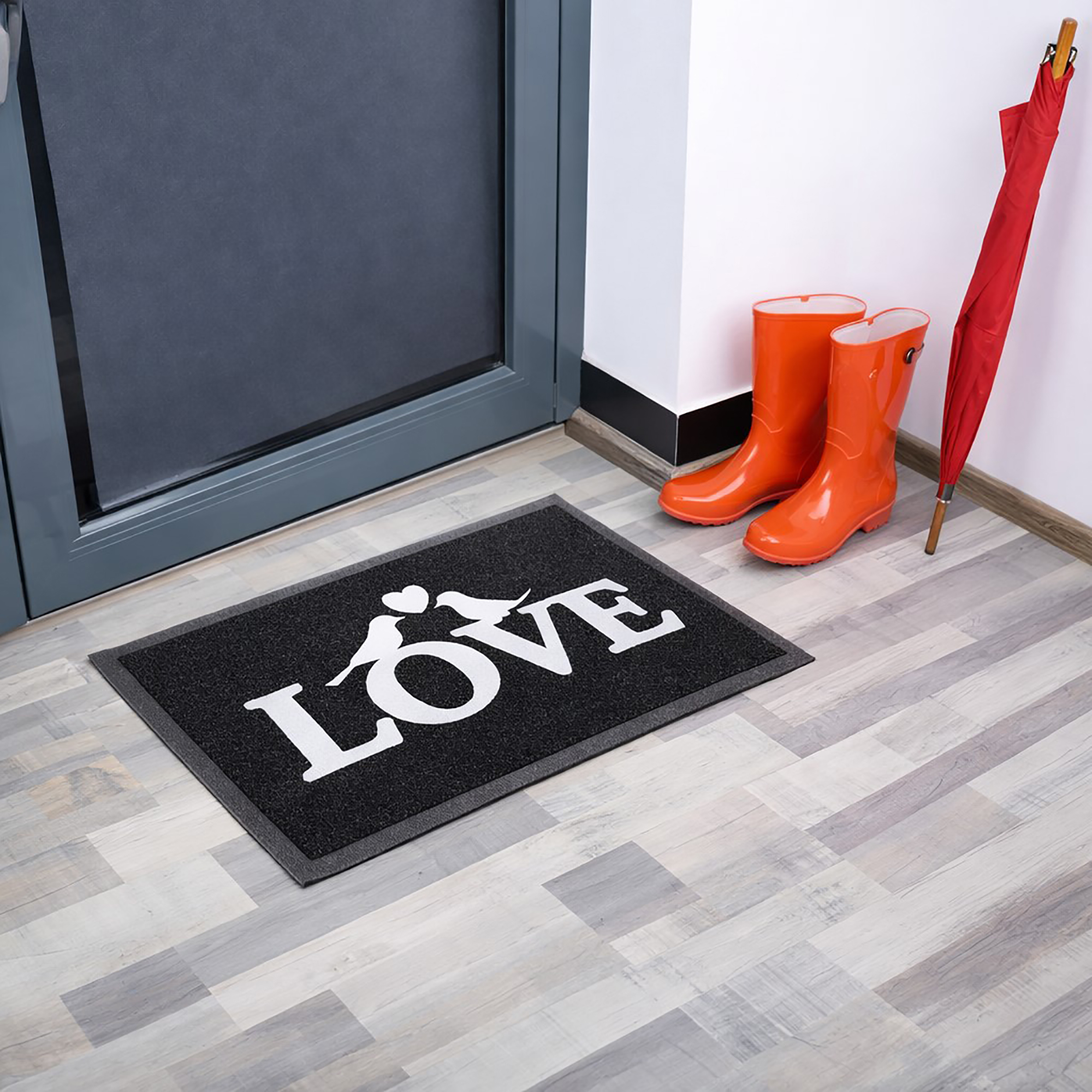 Angled indoor entryway view with black LOVE doormat boots and umbrella