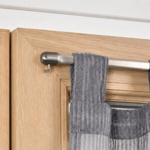 Close-up of a brushed nickel cafe curtain rod resting on a mounting hook attached to a wooden window frame.