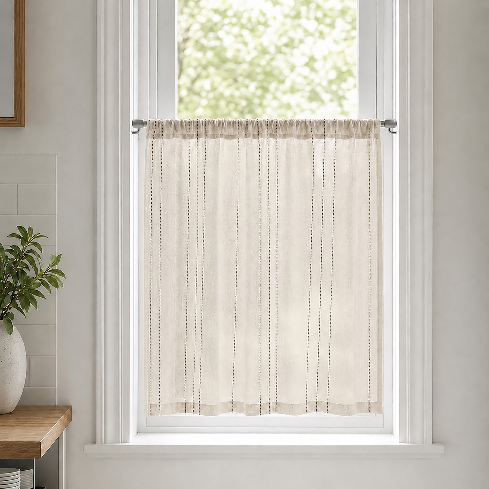 Small kitchen window featuring a sheer off-white curtain with thin vertical stripes mounted on a silver cafe rod.