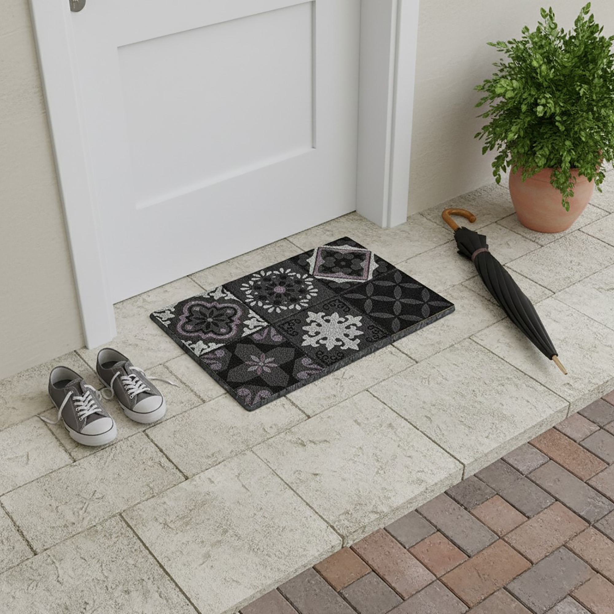 Patterned cement-tile doormat placed at white door with shoes and umbrella