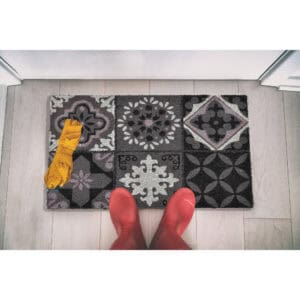 Cement-tile printed doormat seen from above with boots and umbrella