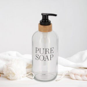 Clear glass soap dispenser with pure soap print isolated on white background