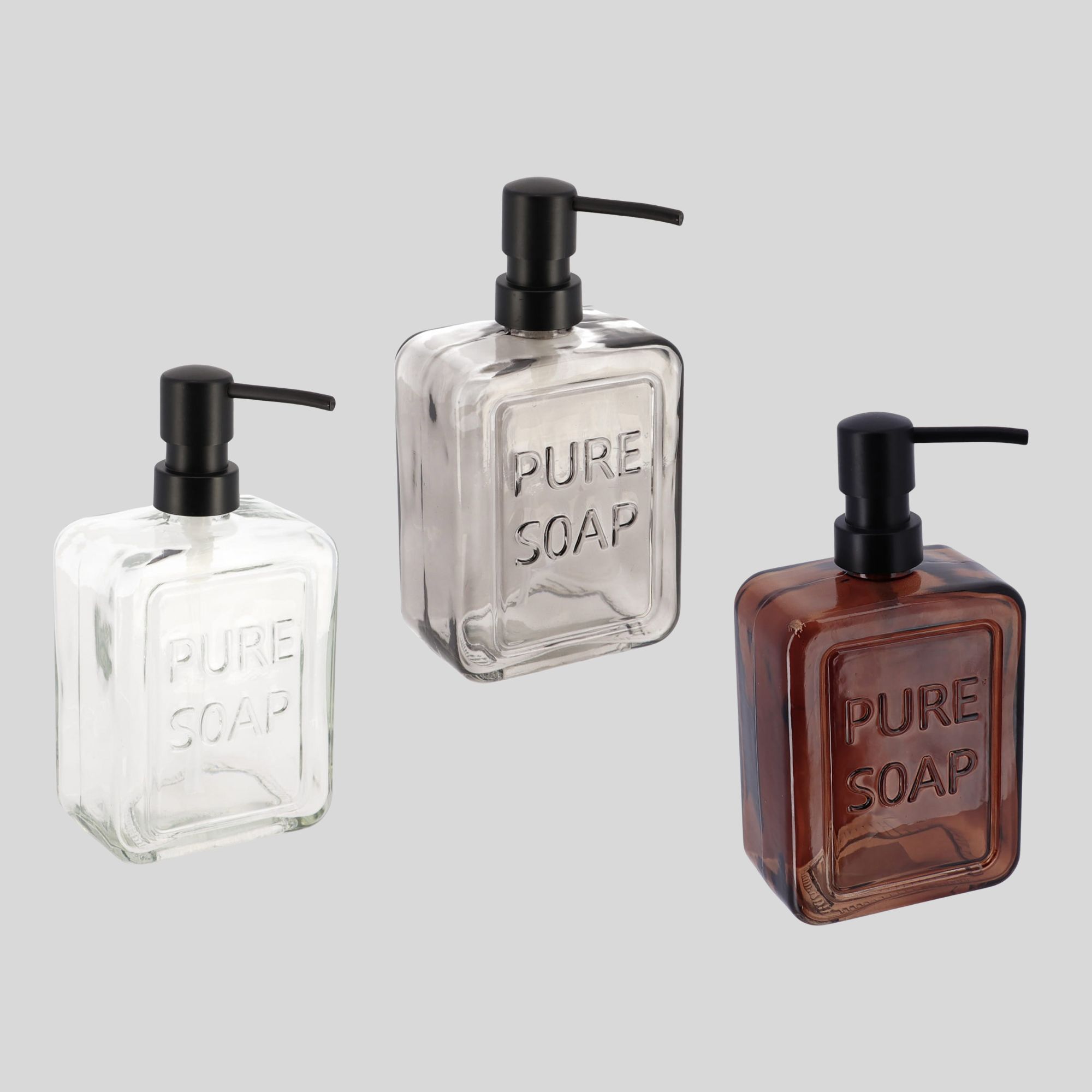 Trio of glass soap dispensers in clear gray and amber with black pumps isolated on light background
