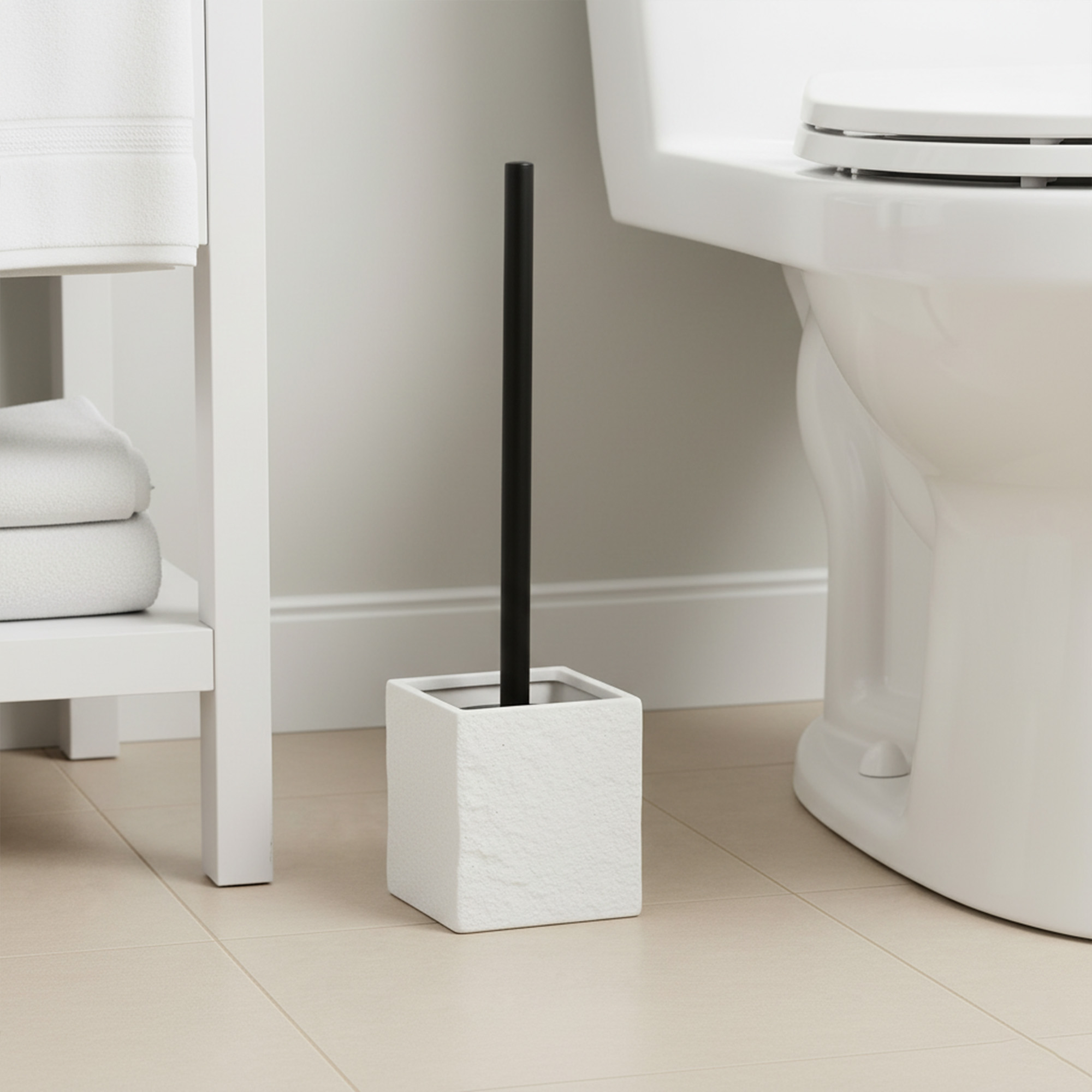 White marble-look toilet brush holder with black handle in modern bathroom