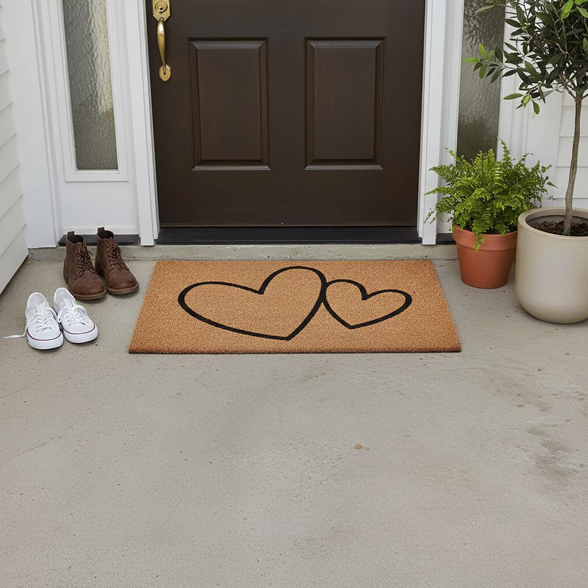 Large hearts coir doormat in front of brown door with shoes and potted plants