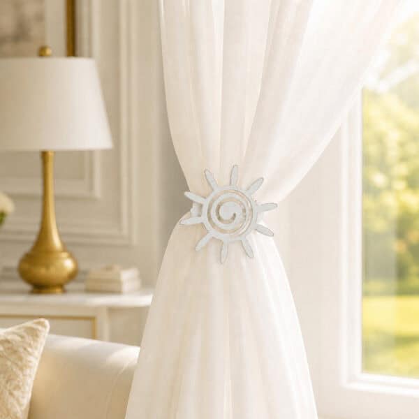 2- Ivory sheer curtain held to one side by a white gold sun tieback in a refined living room with a gold lamp.