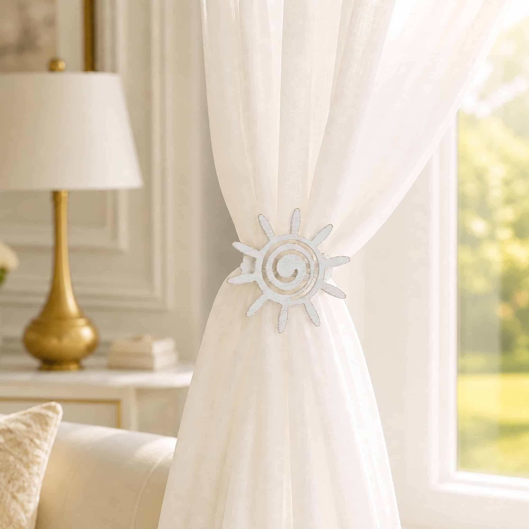 2- Ivory sheer curtain held to one side by a white gold sun tieback in a refined living room with a gold lamp.