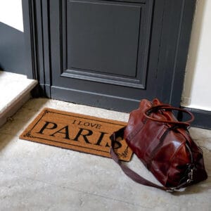 printed front door mat in situation outside at entrance door with travel bag