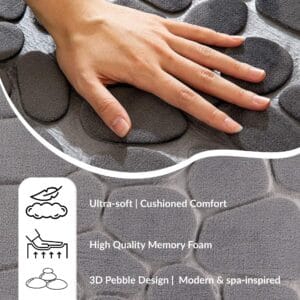 Hand pressing into a cushioned dark gray pebble mat illustrating softness, memory foam filling, and spa-inspired comfort