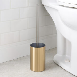 Brushed gold toilet brush holder with chrome handle beside white toilet against white subway tile