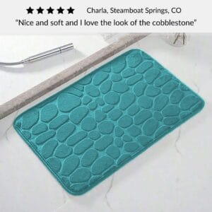 Peacock blue bath mat with cobblestone pattern placed near shower on bathroom floor with customer review praising softness and design