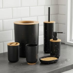 Black bathroom accessory set with bamboo accents on wet countertop