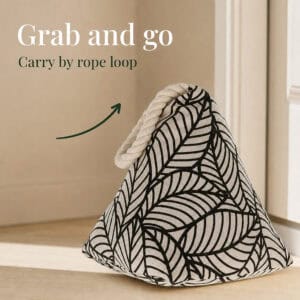 Black leaf print cone door stopper against a door with an arrow pointing to its rope loop. On-image text: "Grab and go," "Carry by rope loop."