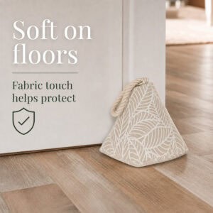 White leaf print cone door stopper propping open a white door on hardwood floor, with a shield icon. On-image text: "Soft on floors," "Fabric touch helps protect."