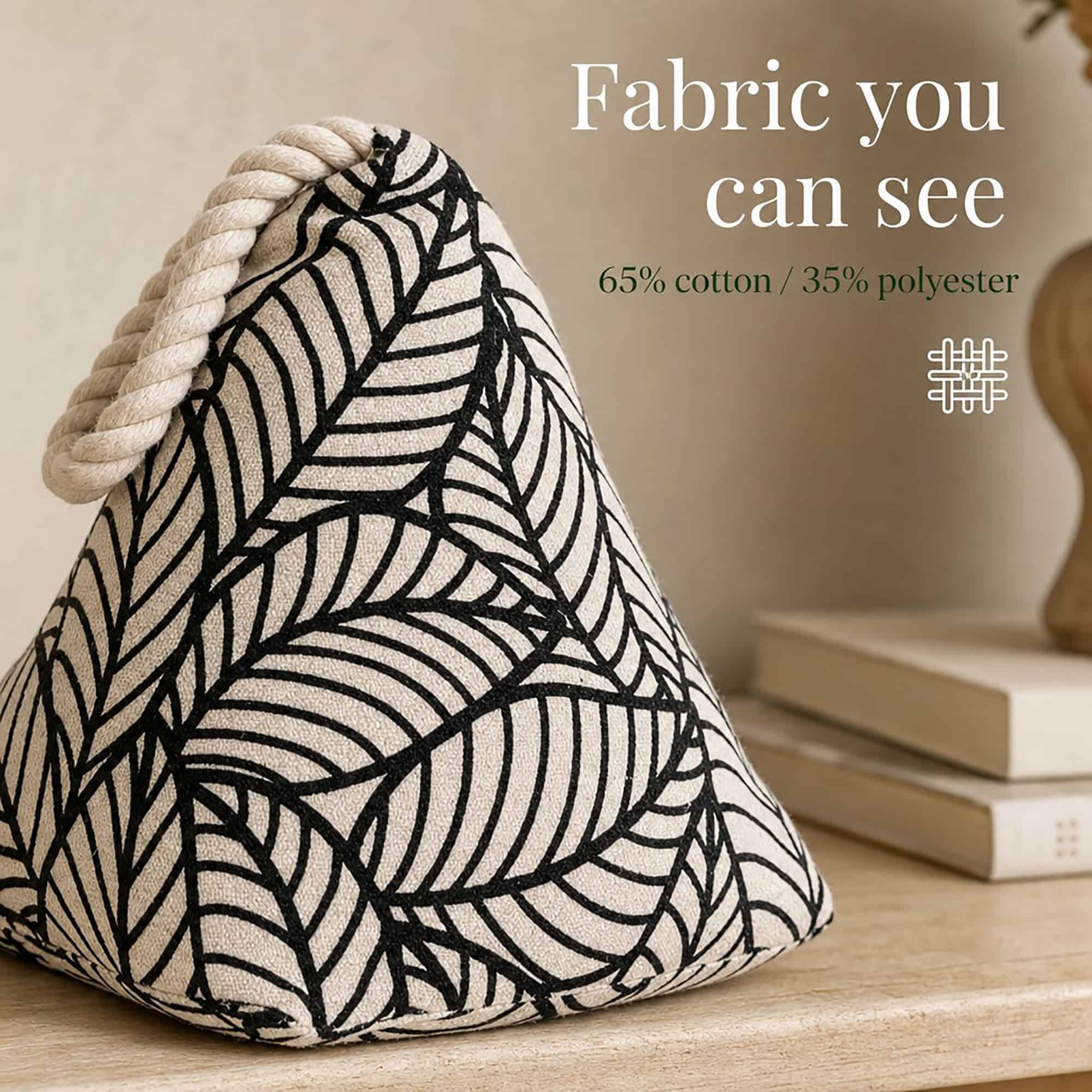 Black leaf print cone door stopper on a wood surface beside books, with a weave icon. On-image text: "Fabric you can see," "65% cotton / 35% polyester."