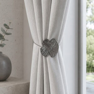 Lifestyle minéral: Polished graphite water lily curtain tieback on a light linen curtain in a minimal stone-toned room