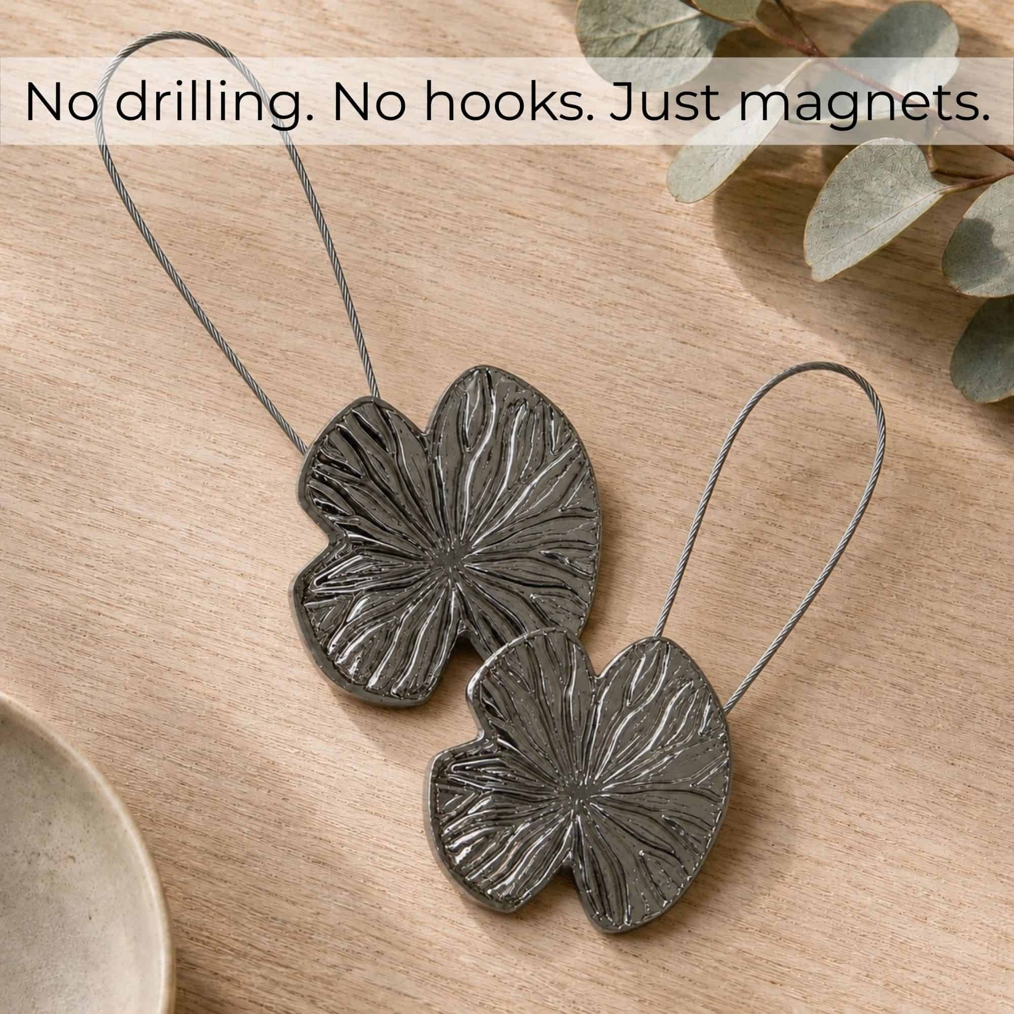 Flat-lay bois: Set of 2 polished graphite water lily magnetic curtain tiebacks on light wood, no drilling no hooks just magnets